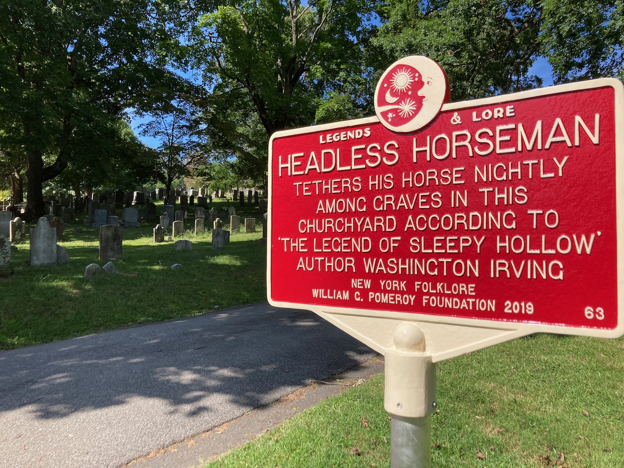Sign that reads HEADLESS HORSEMAN TETHERS HIS HORSE NIGHTLY AMONG THE GRAVES IN THIS CHURCHYARD ACCORDING TO THE LEGEND OF SLEEPY HOLLOW.