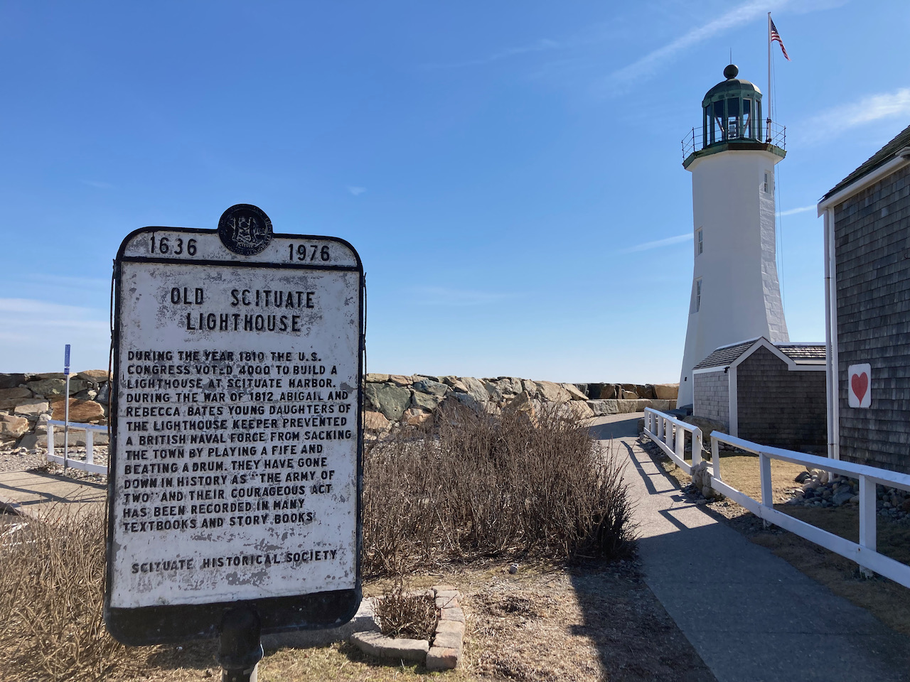 Sign outside of Scituate Lighthouse (with lighthouse in background) that tells the story of Rebecca and Abigail Bates.