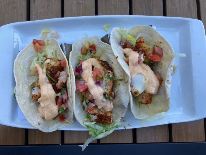 Three fish tacos on white plate.