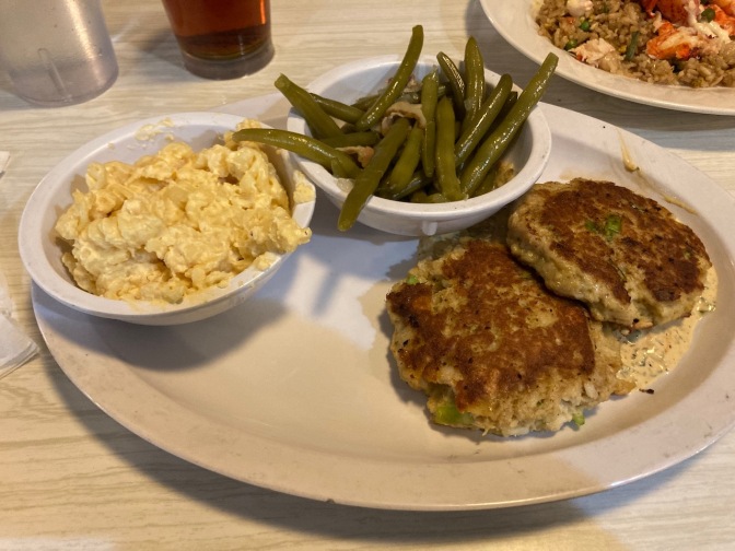 Crab cakes on plate, with sides of green beans and macaroni and cheese.